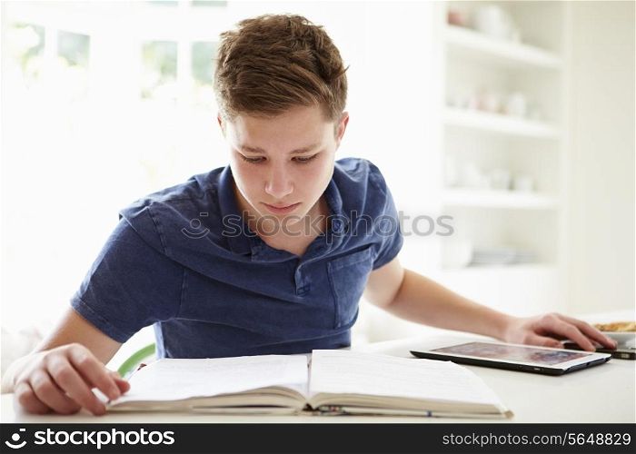 Teenage Boy Studying Using Digital Tablet At Home