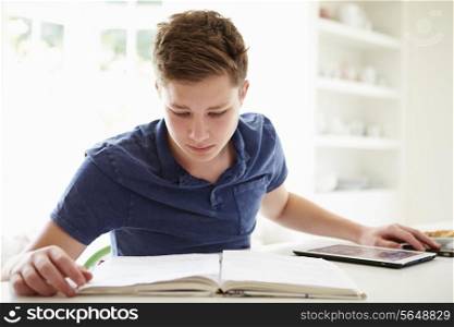 Teenage Boy Studying Using Digital Tablet At Home