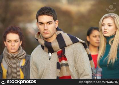 Teenage Boy Surrounded By Friends In Outdoor Autumn Landscape