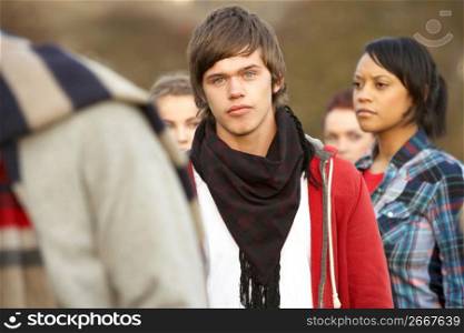 Teenage Boy Surrounded By Friends In Outdoor Autumn Landscape