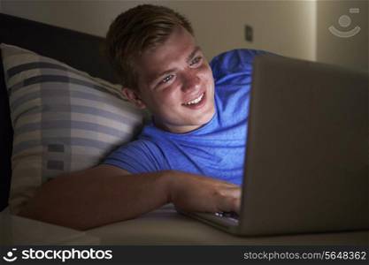 Teenage Boy Using Laptop In Bed At Night