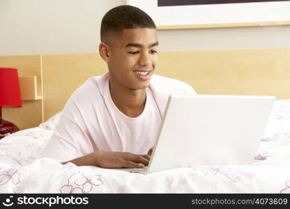 Teenage Boy Using Laptop In Bedroom