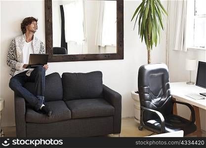 Teenage boy using laptop on couch