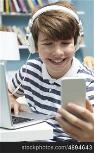 Teenage Boy Using Technology In Bedroom