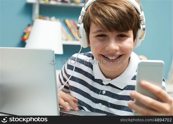 Teenage Boy Using Technology In Bedroom
