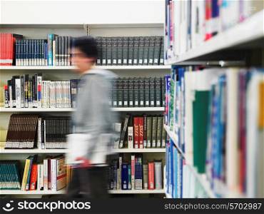 Teenage boy walking through library motion blur