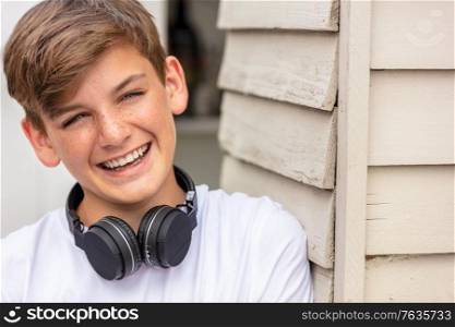 Teenage boy wearing wirless bluetooth headphones and laughing
