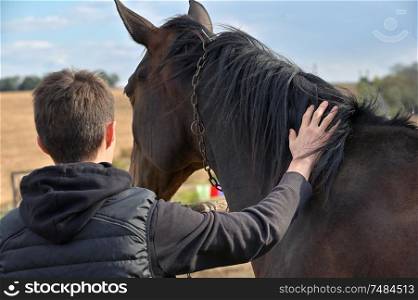 Teenage boy with a horse in nature