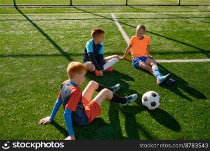Teenage boys football team talking on soccer field resting after training or match. Teenage boys football team talking on soccer field