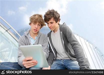 Teenage boys sitting outside with electronic tablet