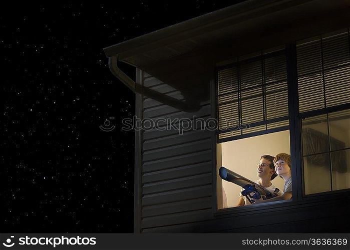 Teenage boys stand with telescope at open window looking at night sky