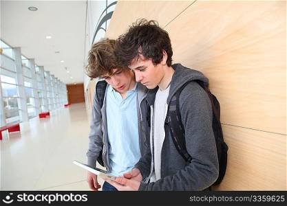 Teenage boys using electronic tablet in school hall