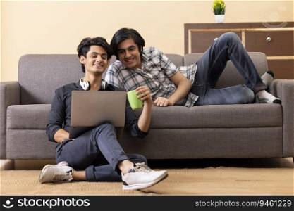 Teenage boys using laptop together while sitting on floor in living room