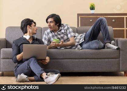 Teenage boys using laptop together while sitting on floor in living room