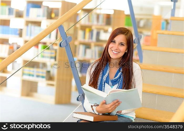 Teenage brunette student on high school library stairs reading book
