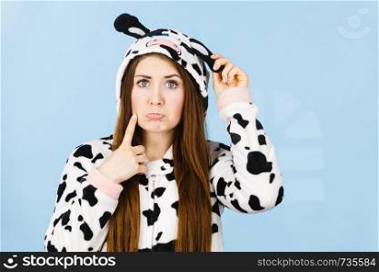 Teenage confused girl in funny nightclothes, pajamas cartoon style making silly face, woman in doubt, studio shot on blue.. Teen confused girl wearing pajamas cartoon