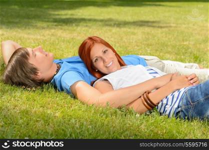 Teenage couple enjoying sun lying together on grass relaxing