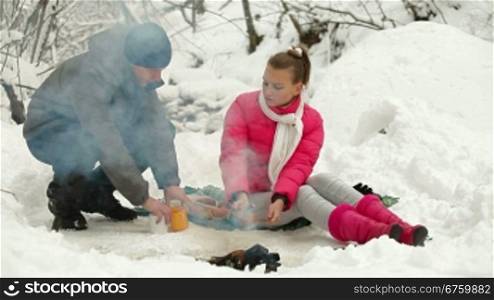 Teenage Couple Enjoying Winter Holidays by Bonfire in Snowy Forest