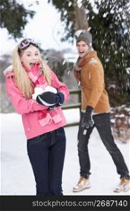 Teenage Couple Having Snowball Fight In Snowy Landscape