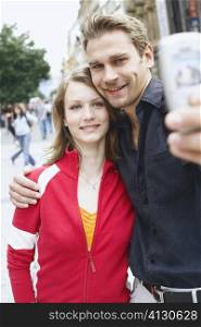 Teenage couple holding a mobile phone for a photograph