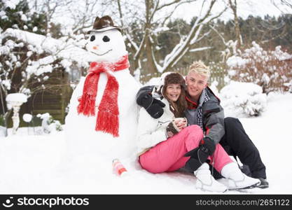 Teenage Couple In Winter Landscape Next To Snowman With Flask And Hot Drink