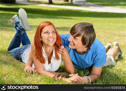 Teenage couple lying on grass laughing together enjoy summer day