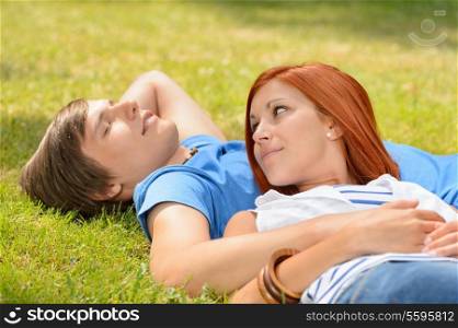 Teenage couple lying on grass summer girl looking at boyfriend
