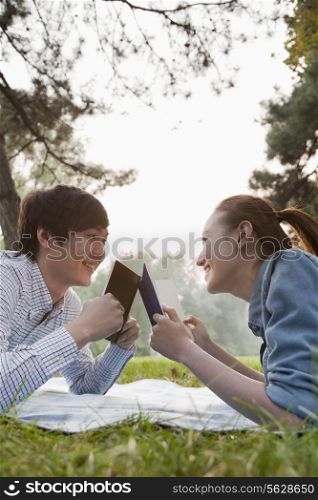 Teenage couple reading books in the park