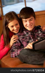 Teenage Couple Relaxing On Sofa With Laptop