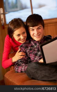 Teenage Couple Relaxing On Sofa With Tablet Computer