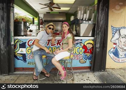 Teenage couple sitting at a bar counter of a juice bar