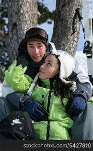 Teenage couple sitting on a ski slope