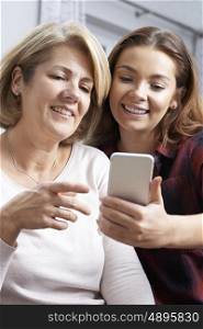 Teenage Daughter Showing Mother How To Use Mobile Phone