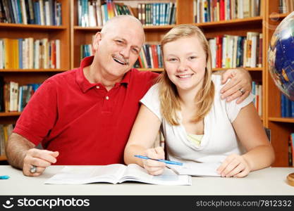 Teenage daughter studying with her father (or teacher) in the school library.