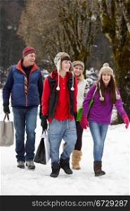 Teenage Family Carrying Shopping Walking Along Snowy Street