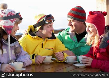 Teenage Family Enjoying Hot Drink In Cafe At Ski Resort