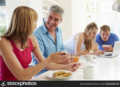 Teenage Family Having Breakfast In Kitchen With Laptop