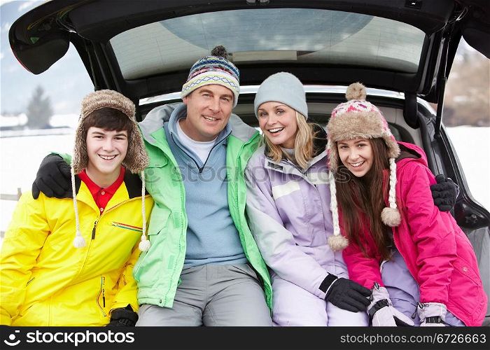 Teenage Family Sitting In Boot Of Car Wearing Winter Clothes