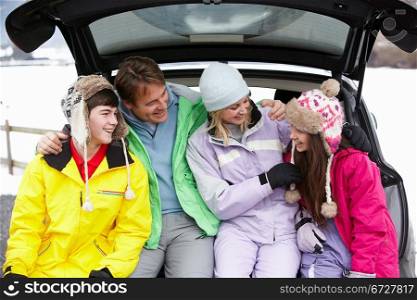 Teenage Family Sitting In Boot Of Car Wearing Winter Clothes