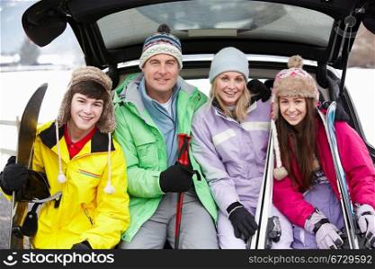 Teenage Family Sitting In Boot Of Car With Skis