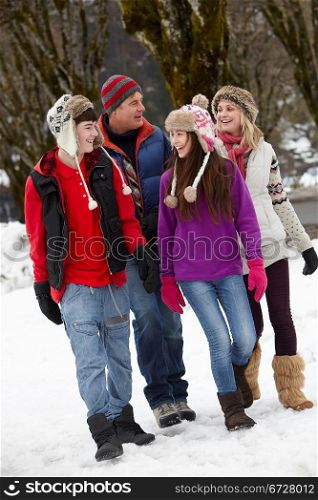 Teenage Family Walking Along Snowy Street In Ski Resort