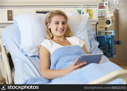 Teenage Female Patient Relaxing In Hospital Bed With Digital Tablet