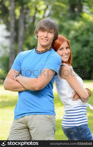 Teenage friends couple leaning against each other in sunny park