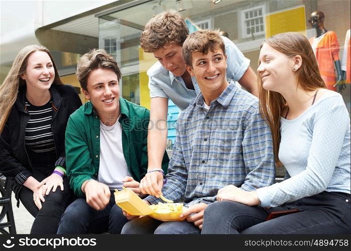 Teenage Friends Hanging Out In Town Together Eating Takeaway Food