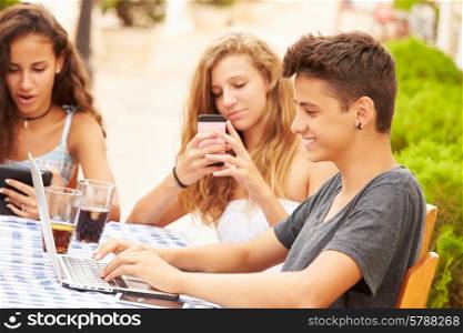 Teenage Friends Sitting At Caf? Using Digital Devices