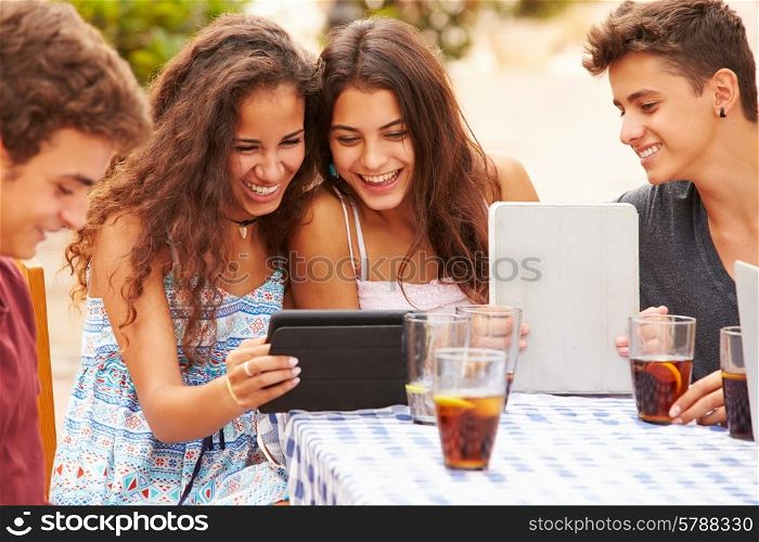 Teenage Friends Sitting At Caf? Using Digital Tablets