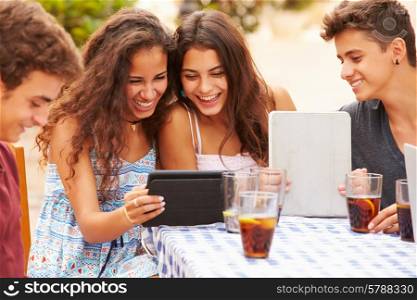 Teenage Friends Sitting At Caf? Using Digital Tablets