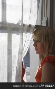 Teenage girl (16-17) looking through window