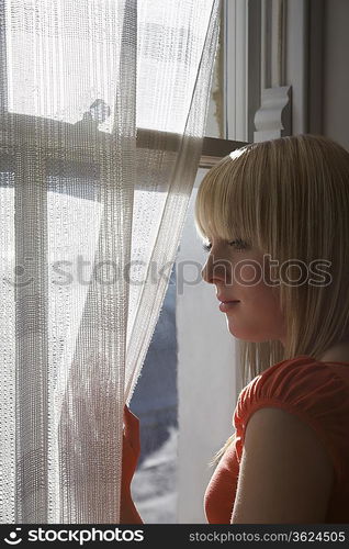 Teenage girl (16-17) looking through window