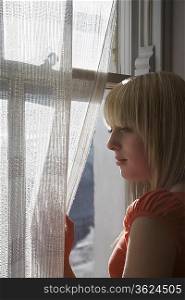Teenage girl (16-17) looking through window